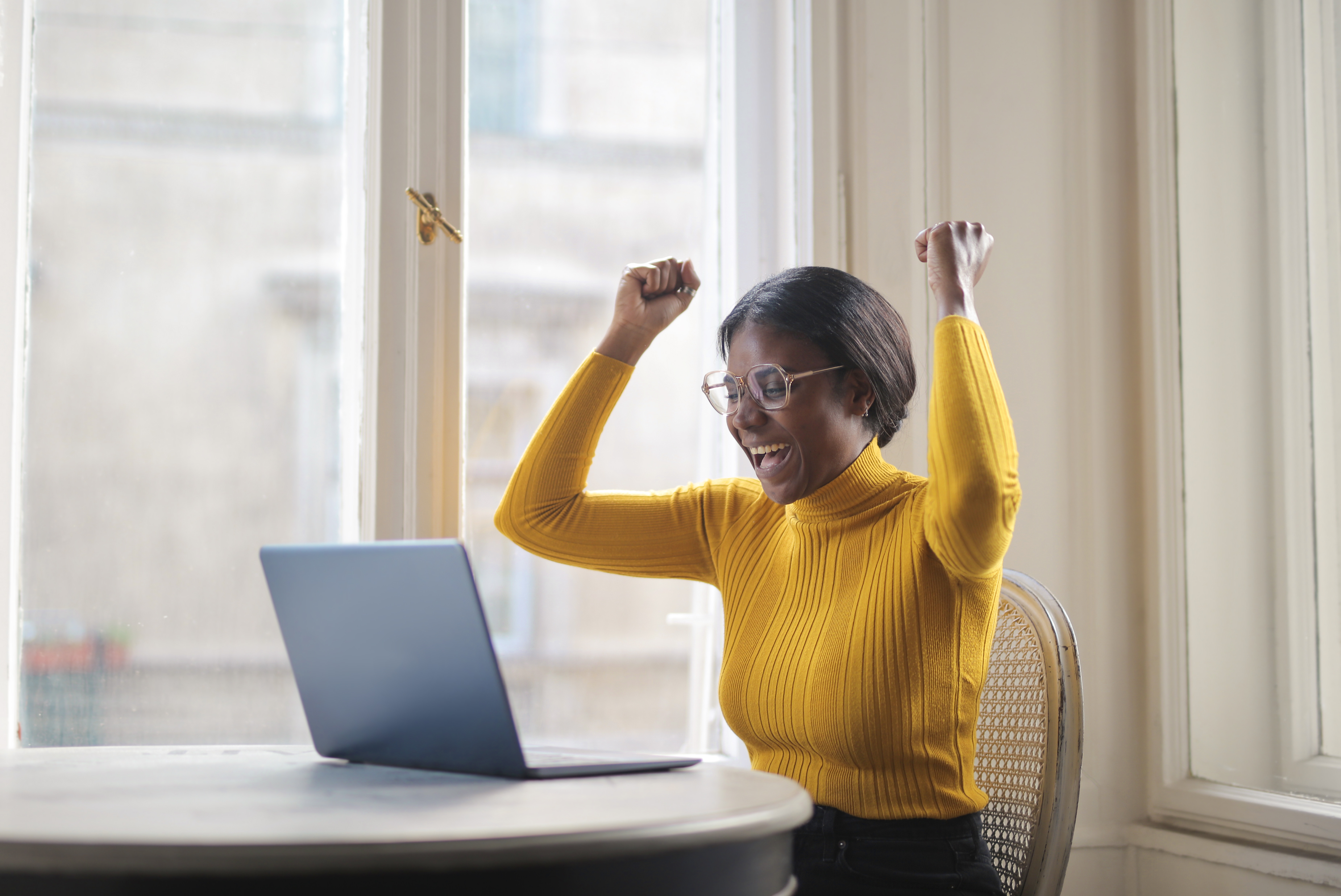 Person celebrating success at laptop